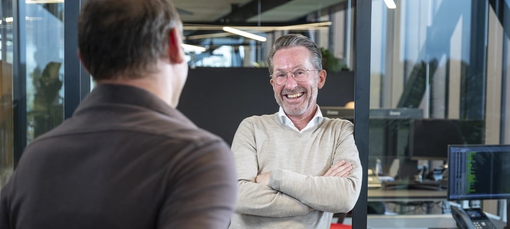 Medewerker KeenSystems lacht naar collega. Foto genomen over schouder.