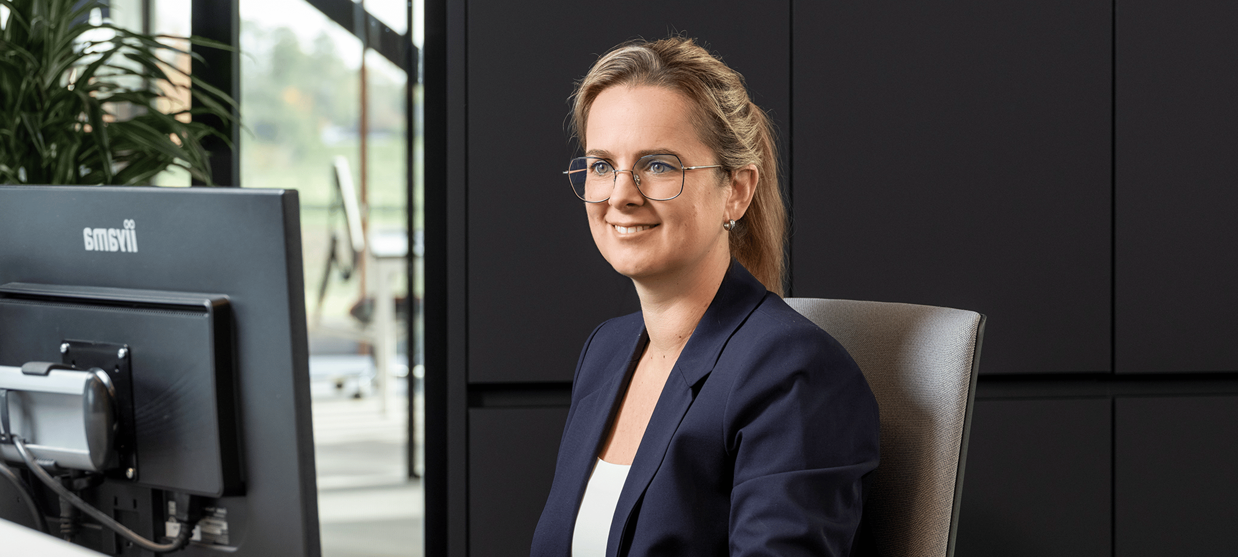 Administratief medewerker van KeenSystems kijkt lachend naar scherm.
