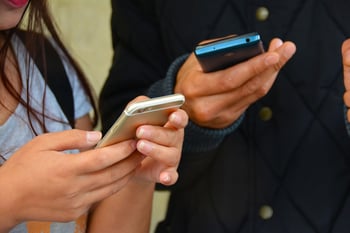 Twee mensen die allebei een mobiele telefoon vasthouden