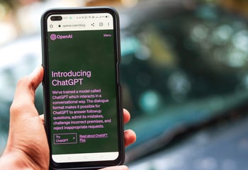 Smartphone met de website van OpenAI en ChatGPT in beeld.