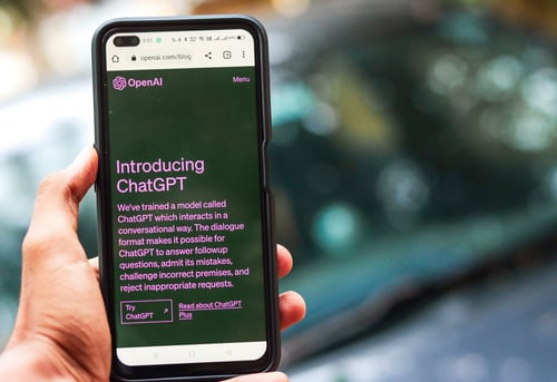 Smartphone met de website van OpenAI en ChatGPT in beeld.