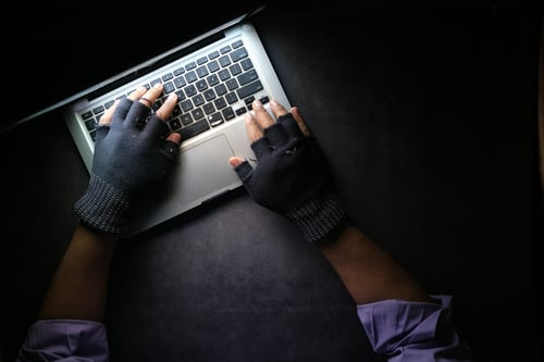 Man met handschoenen aan op laptop